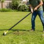 Gardener pushing a scuffle hoe through lawn to remove weeds efficiently