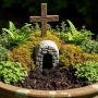 Small resurrection garden container with native ground cover plants surrounding stone tomb entrance and wooden cross