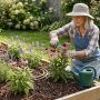 Homeowner watering outdoor plants in a Charlotte NC backyard garden during summer morning